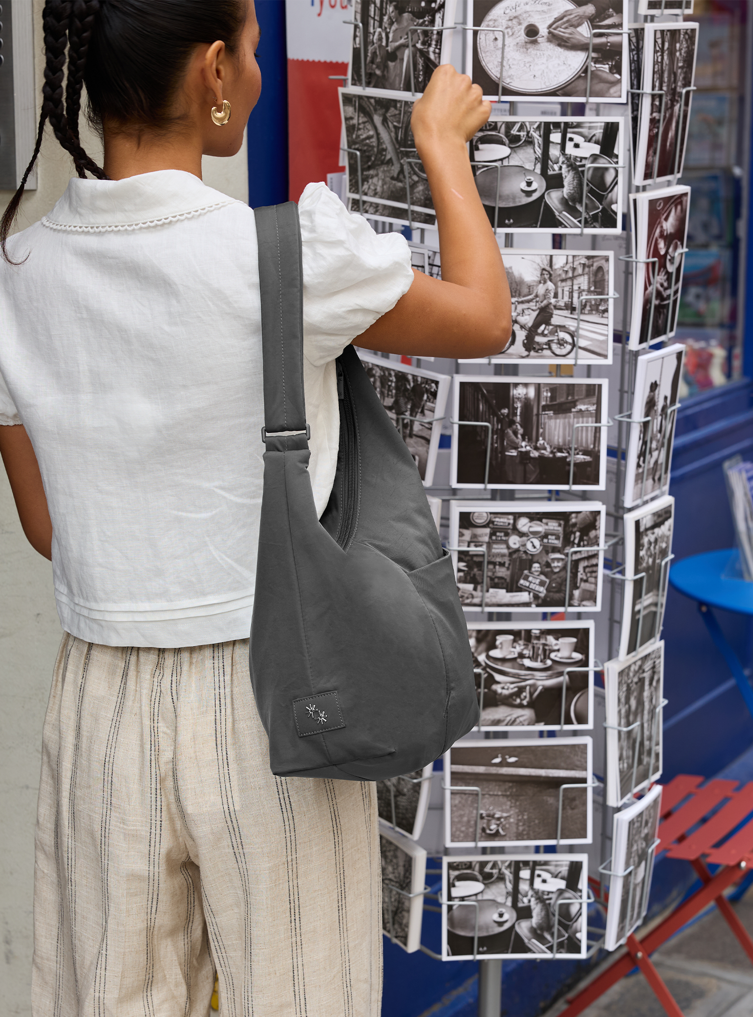 Woman carrying the Midi Arc slouchy hobo bag in dark grey nylon as shoulder bag